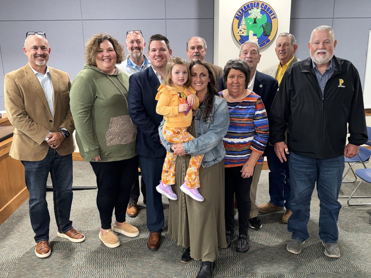 Front row – Jessica Mundy (sister), Justin, Jordyn, & Jayda Mundy, and Sherry & James Mundy (parents); back row – Commissioners Marty Pennell, Josh Lail, Ronnie Reese, Larry Yoder, and Kent Herman.