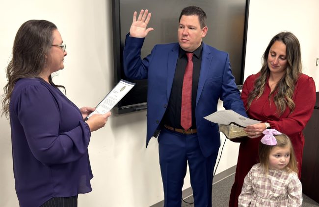 Clerk to the Board Jamie Starnes administers the oath of office to new County Manager Justin Mundy.