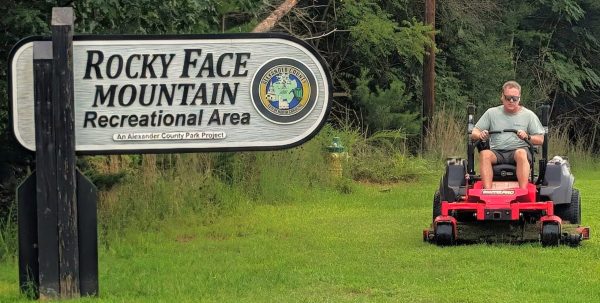 Jason Millsaps operating a riding mower near the entrance sign at Rocky Face Park.